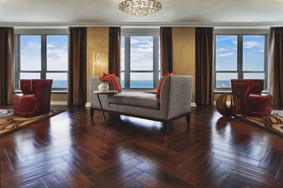 A living room with a couch , chairs , and a view of the ocean.