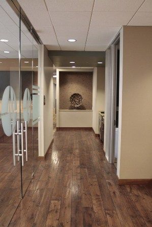 A hallway with hardwood floors and glass doors in an office building.