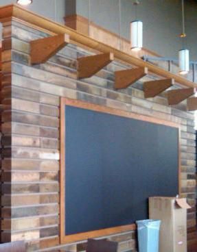 A blackboard is hanging on a brick wall in a room.