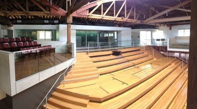 A large auditorium with wooden stairs and a balcony.