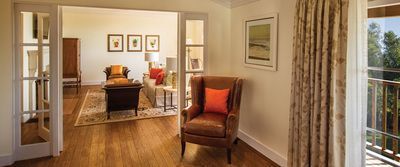 A living room with hardwood floors , a chair , a table and a balcony.