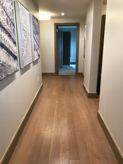 A hallway with hardwood floors and paintings on the wall