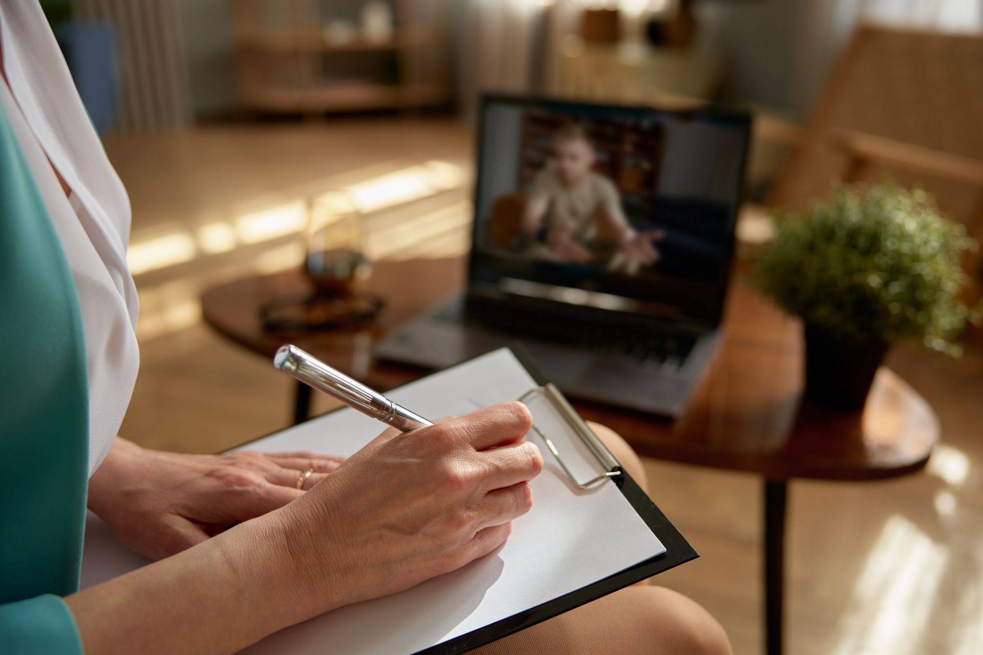 Therapist taking notes during online session.