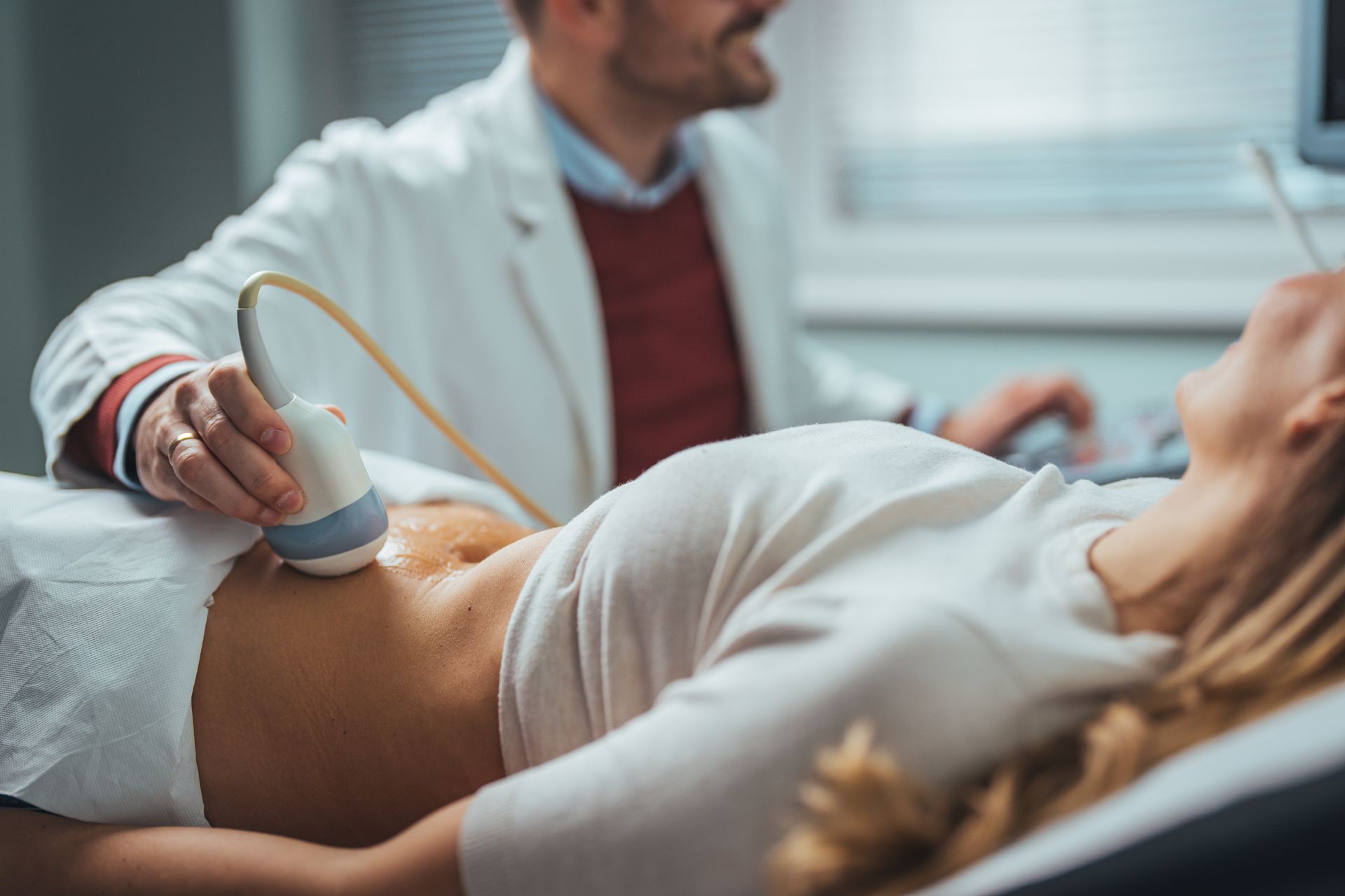 Doctor performing an ultrasound on a patient's abdomen.