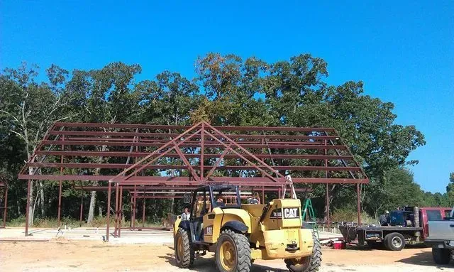 A yellow tractor is parked in front of a building under construction.