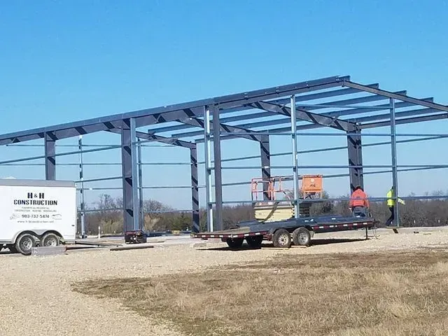 A trailer is being towed to a building under construction.