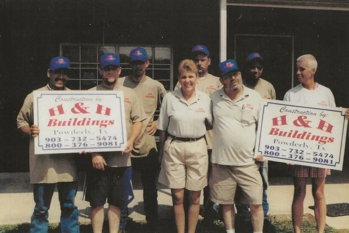 A group of people holding signs that say H & H Buildings.