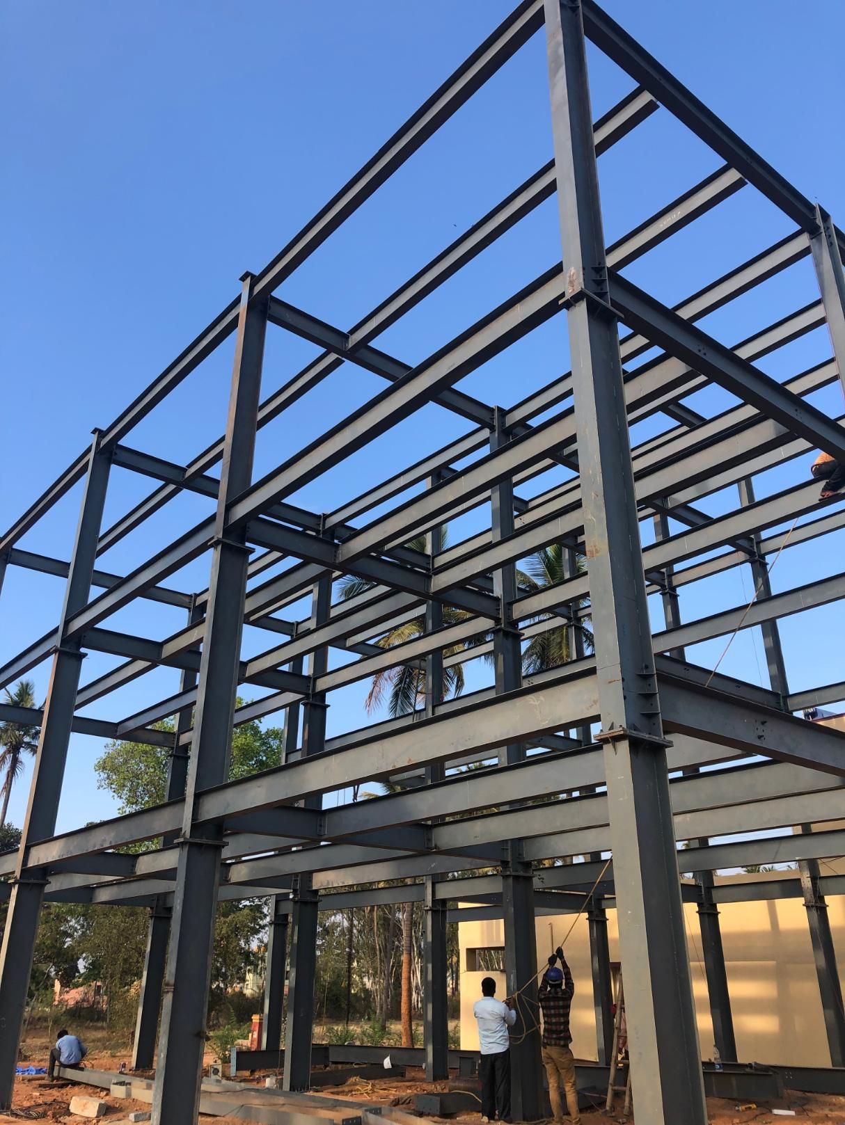 A large metal structure is being built with a blue sky in the background.