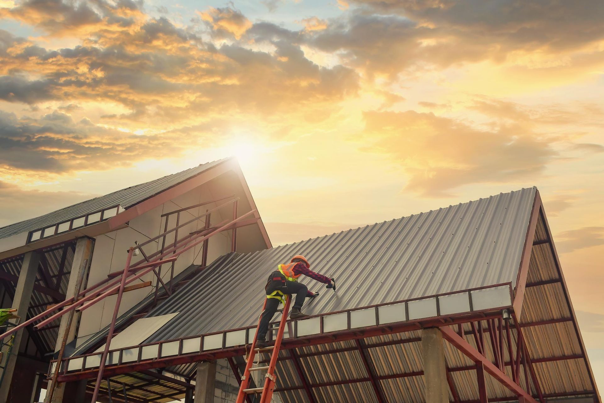 A man on a ladder is working on the roof of a building.