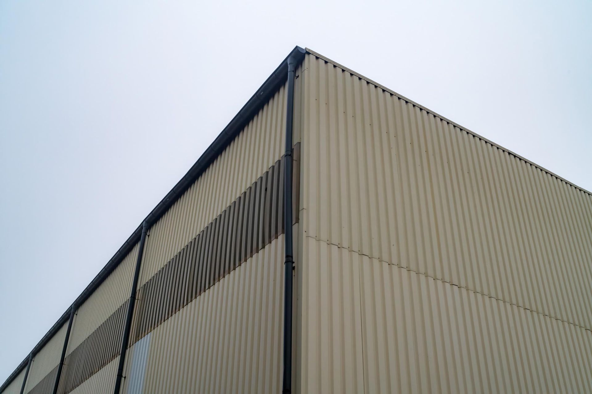 Looking up at the corner of a building with a gutter on it.