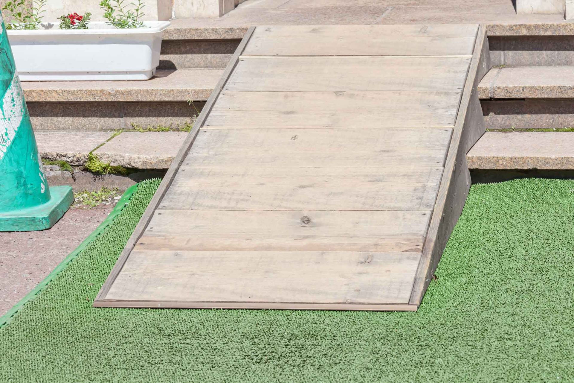 Wooden accessibility ramp over artificial grass beside outdoor steps