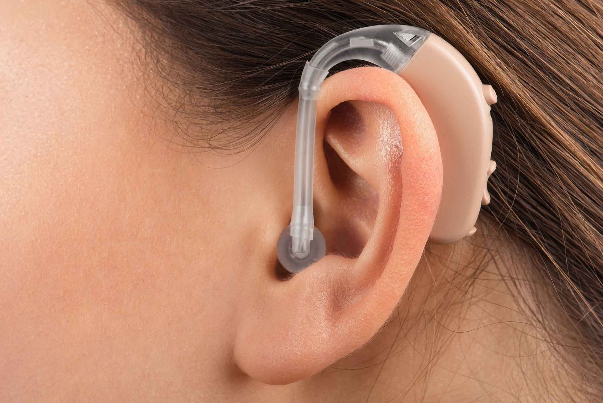 Close-up of a transparent behind-the-ear hearing aid on an ear