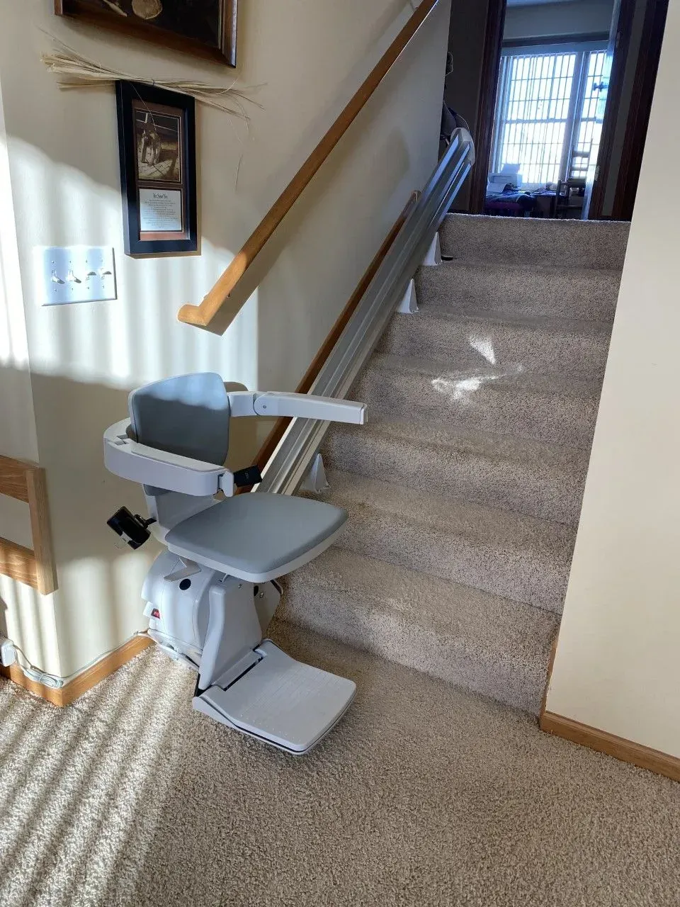 Stairlift installed on a carpeted staircase in a home hallway.