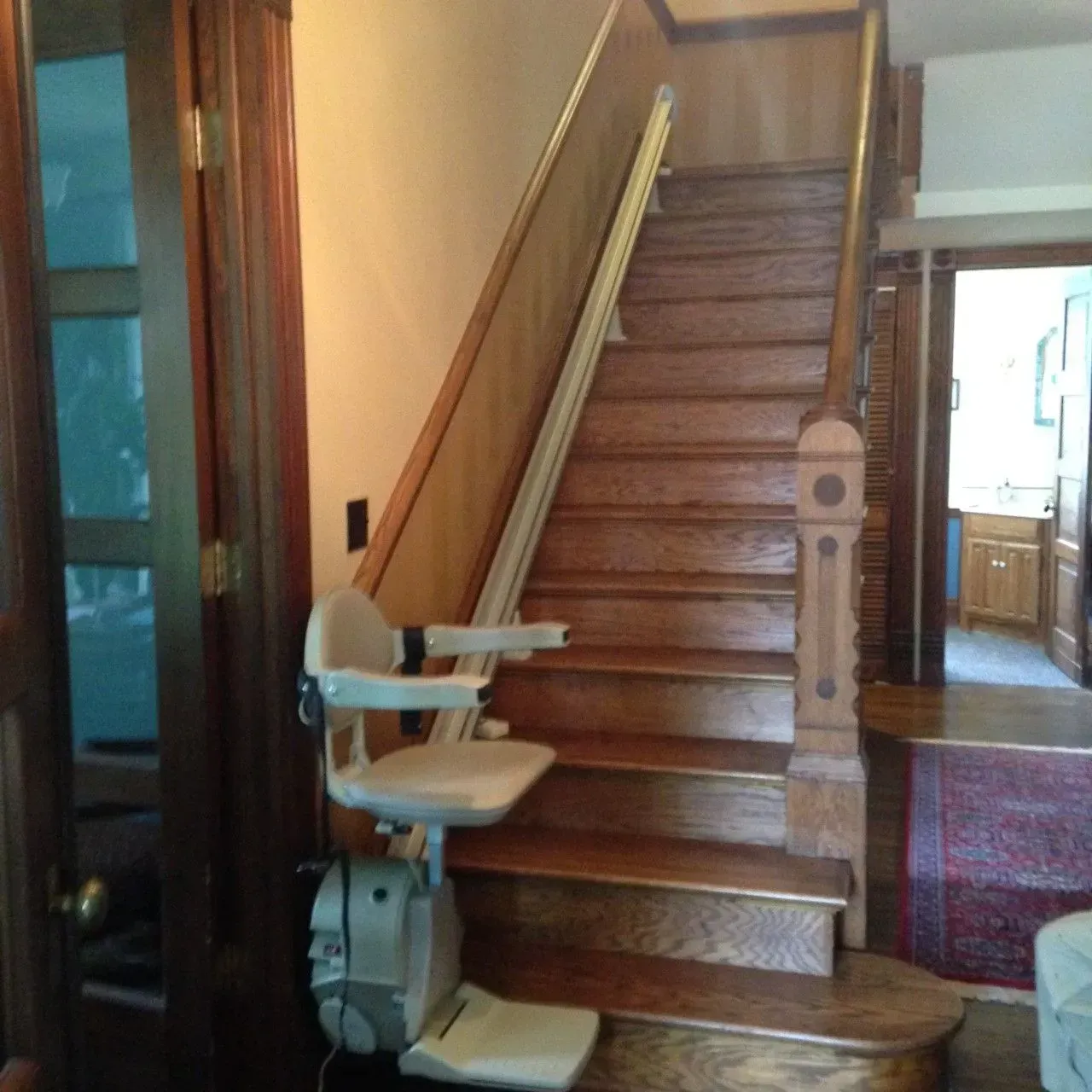 Stair lift beside a wooden staircase in a home interior.