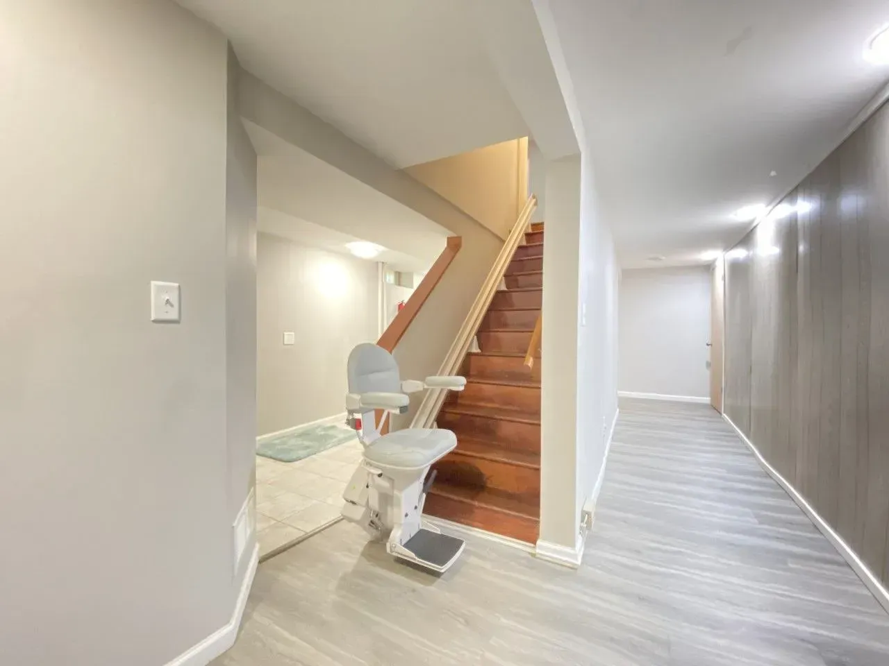 Hallway with carpeted stairs beside a bathroom, featuring a stairlift on the staircase.