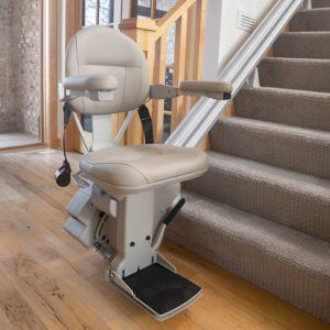 Indoor stair lift chair beside a carpeted staircase in a home hallway