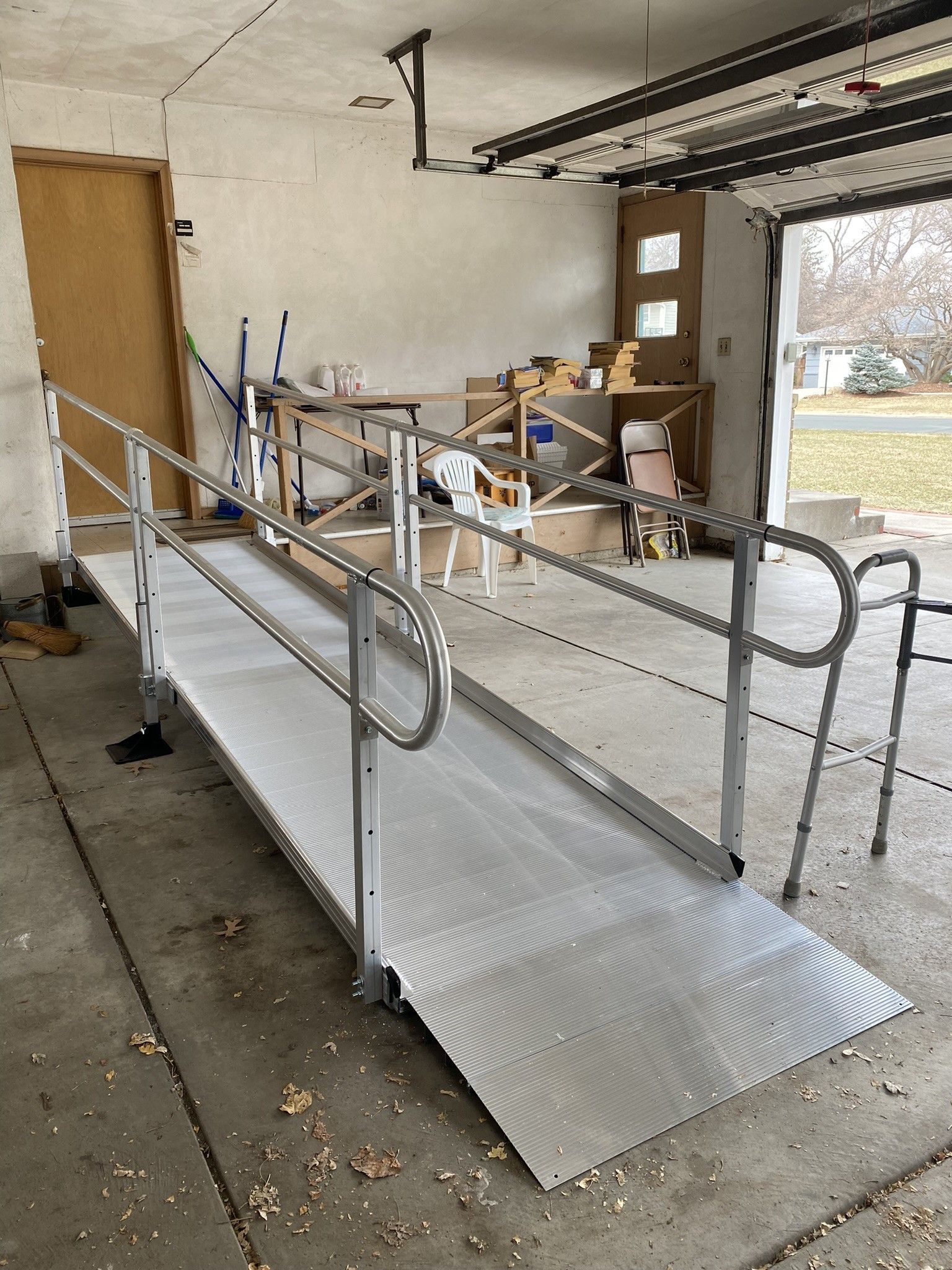 Accessible ramp with metal handrails leading into a garage or workshop area