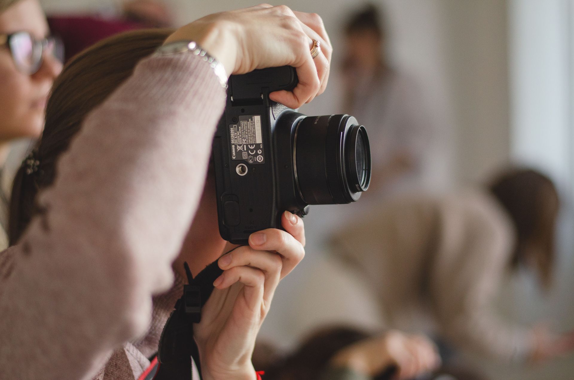 Person photographing with a black camera in an indoor setting