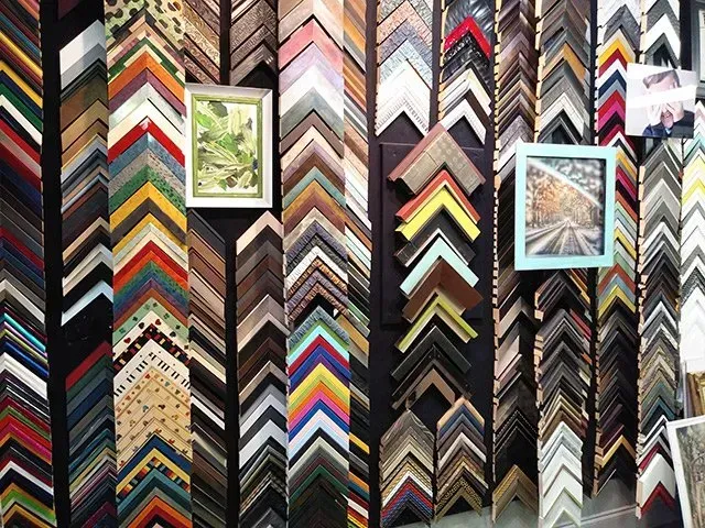 Wall of colorful picture frames arranged in chevron patterns, with two framed artworks hanging among them