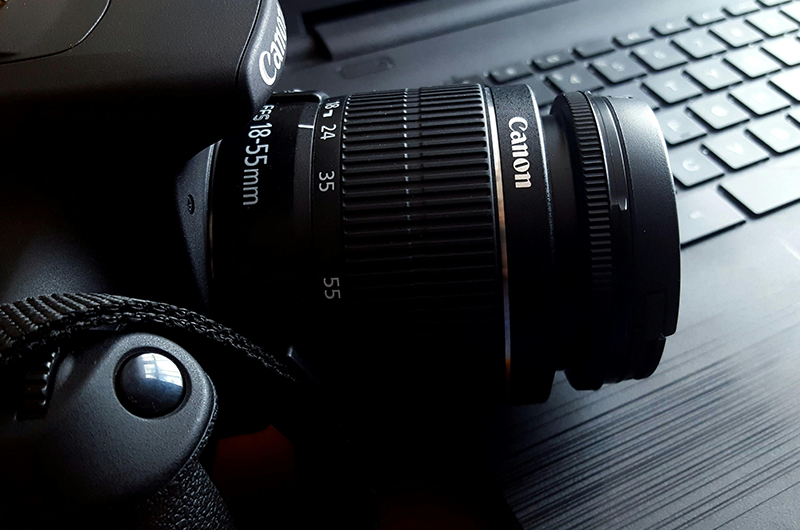 Canon camera lens on a keyboard with a computer mouse nearby