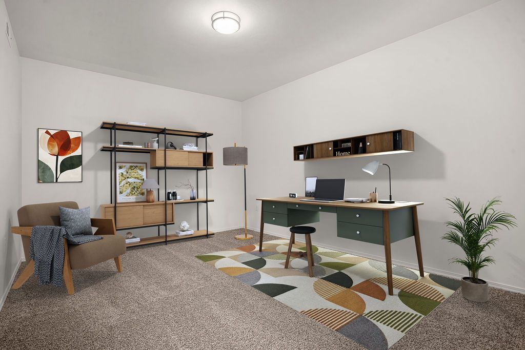 Modern home office with desk, shelving, chair, rug, and a potted plant in a bright minimalist room at Creekside Village apartments in Sandy, UT.