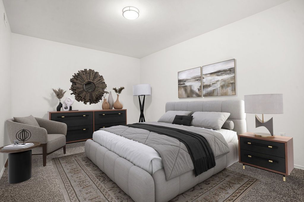 Modern neutral bedroom with a gray bed, patterned rug, dark dresser, and framed wall art at Creekside Village apartments in Sandy, UT.