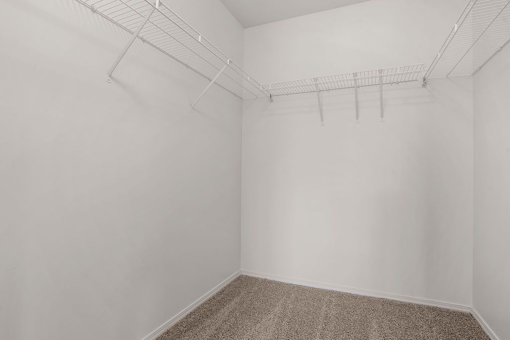 Empty white walk-in closet with wire shelving and carpeted floor at Creekside Village apartments in Sandy, UT.