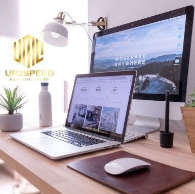 Modern workspace with laptop, monitor, desk lamp, mouse, and plant on a wooden desk