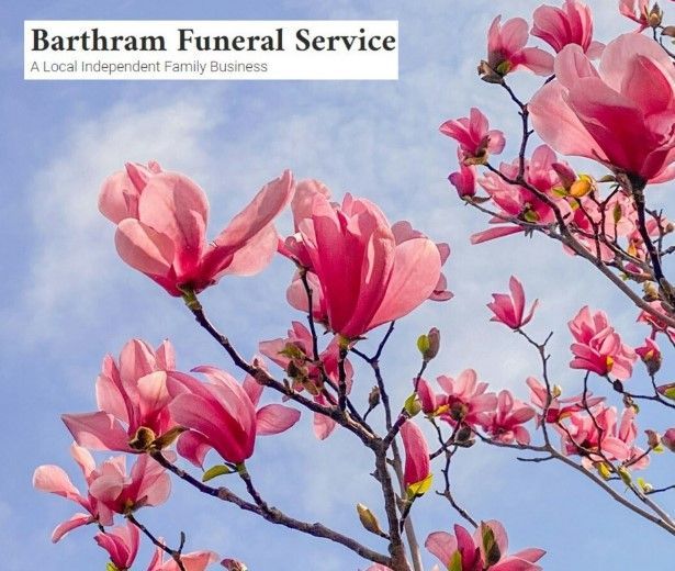 Pink magnolia blossoms against a blue sky with Bartham Funeral Service logo in the corner