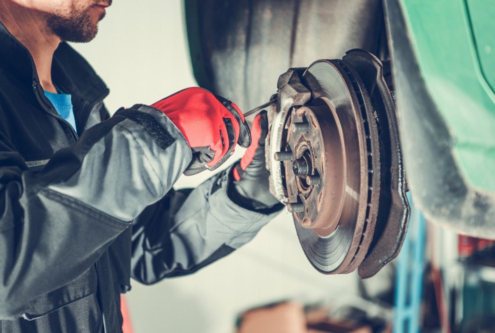 A Man Is Fixing A Brake Disc On A Car In A Garage — Fase Automotive In Sunset ,QLD
