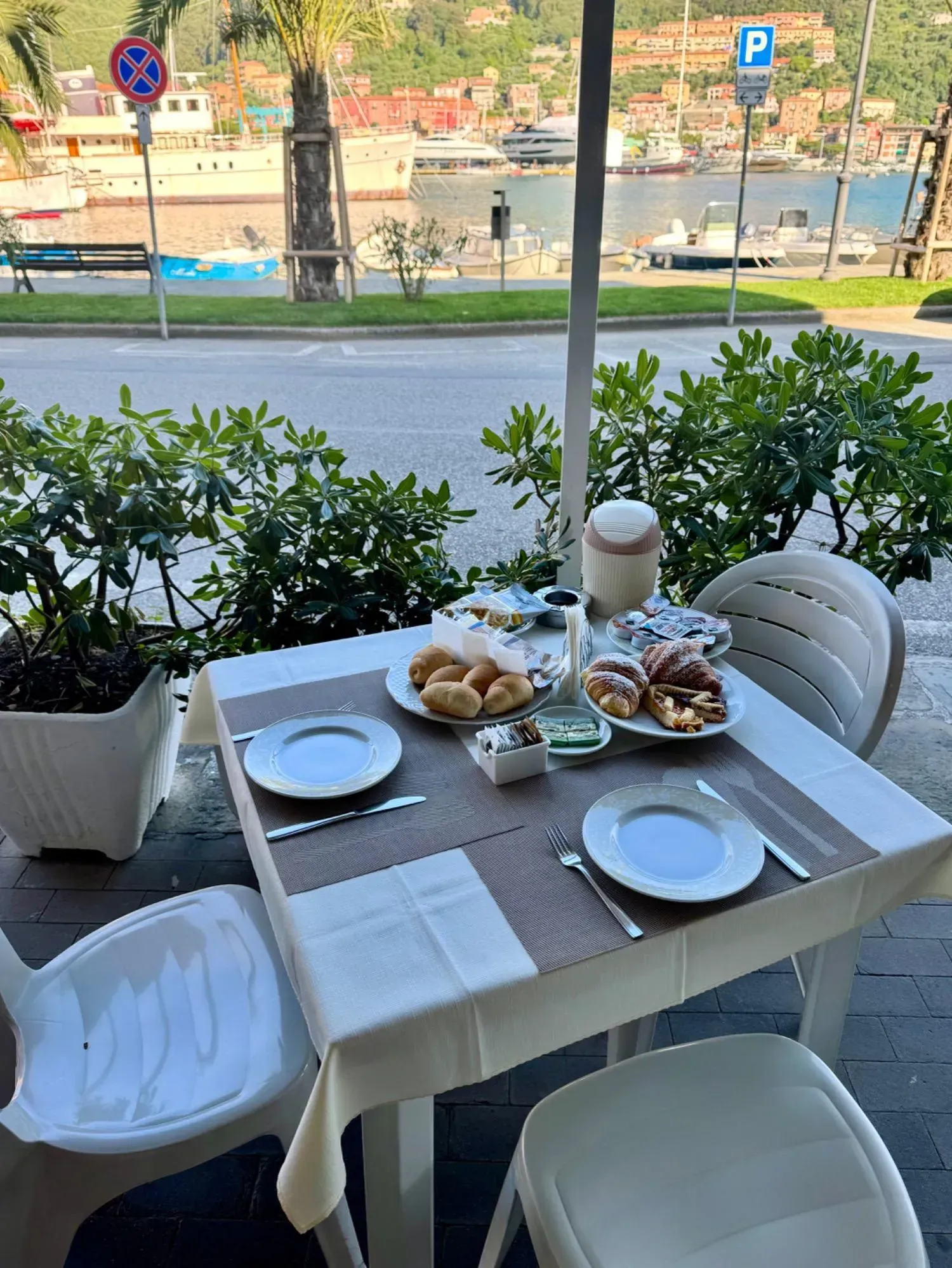 Tavolino all'aperto con piatti per la colazione, affacciato sul lungomare.