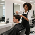 Stylist cutting a client’s hair in a modern salon with mirrors and chairs