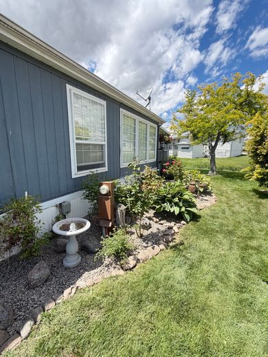 Suburban house with green lawn, sidewalk, and a small white mailbox in front under cloudy sky