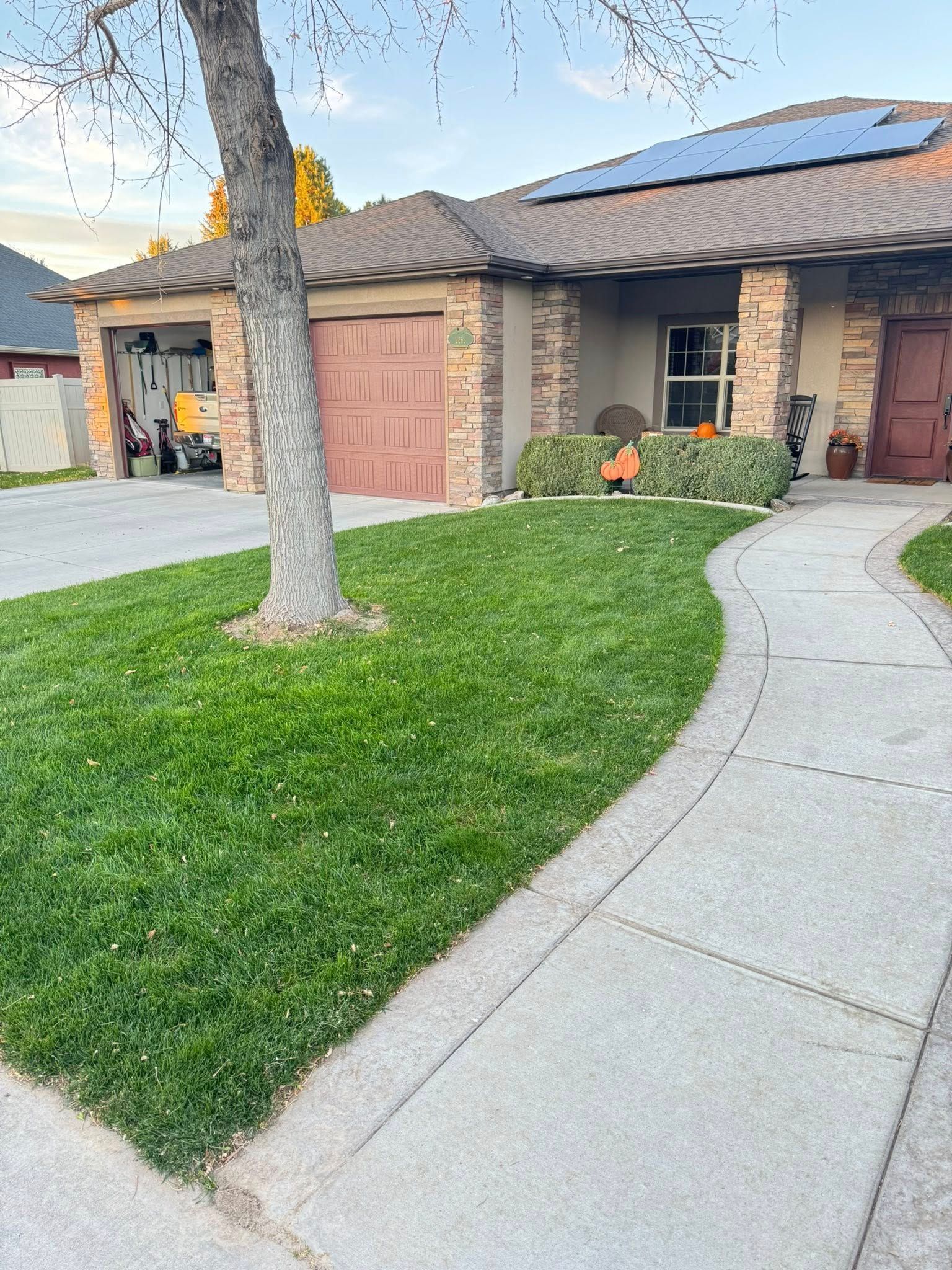 Suburban house exterior with stone facade, garage, green lawn, and curved concrete walkway