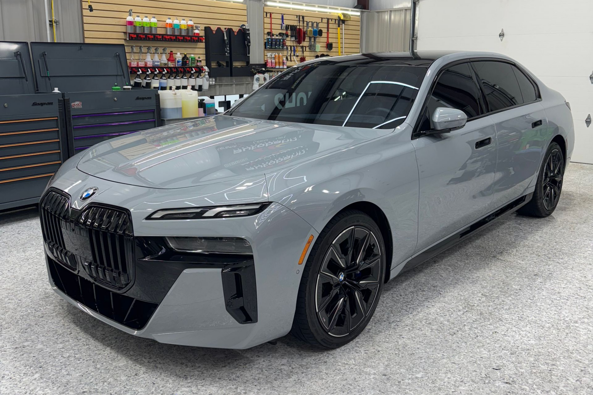 Gray BMW sedan displayed indoors in a showroom, front-left view.