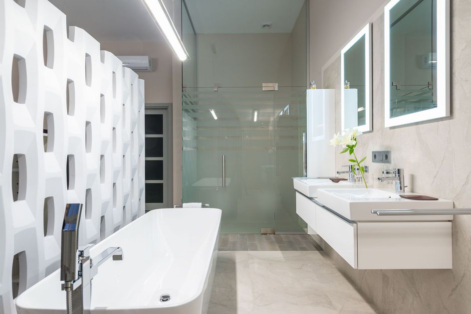 Modern bathroom with white tub, sink vanity, glass shower, and patterned wall tiles