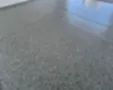 Blurred gray speckled floor with a bright blue reflection on the right side