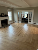 Bright living room with hardwood floors, fireplace, and French doors leading to a dining area.