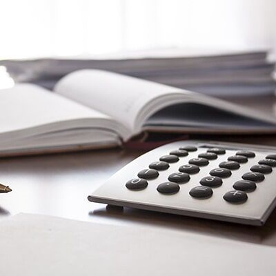 A Calculator Sits On A Desk Next To A Book - Individual & Business Taxation & Financial Planning in Mackay