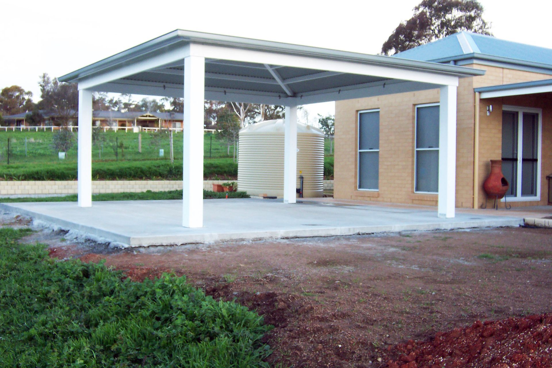 A Tan Brick House With a Newly Installed White Carport Roof — The Gazebo and Shade Centre in Jindera, NSW