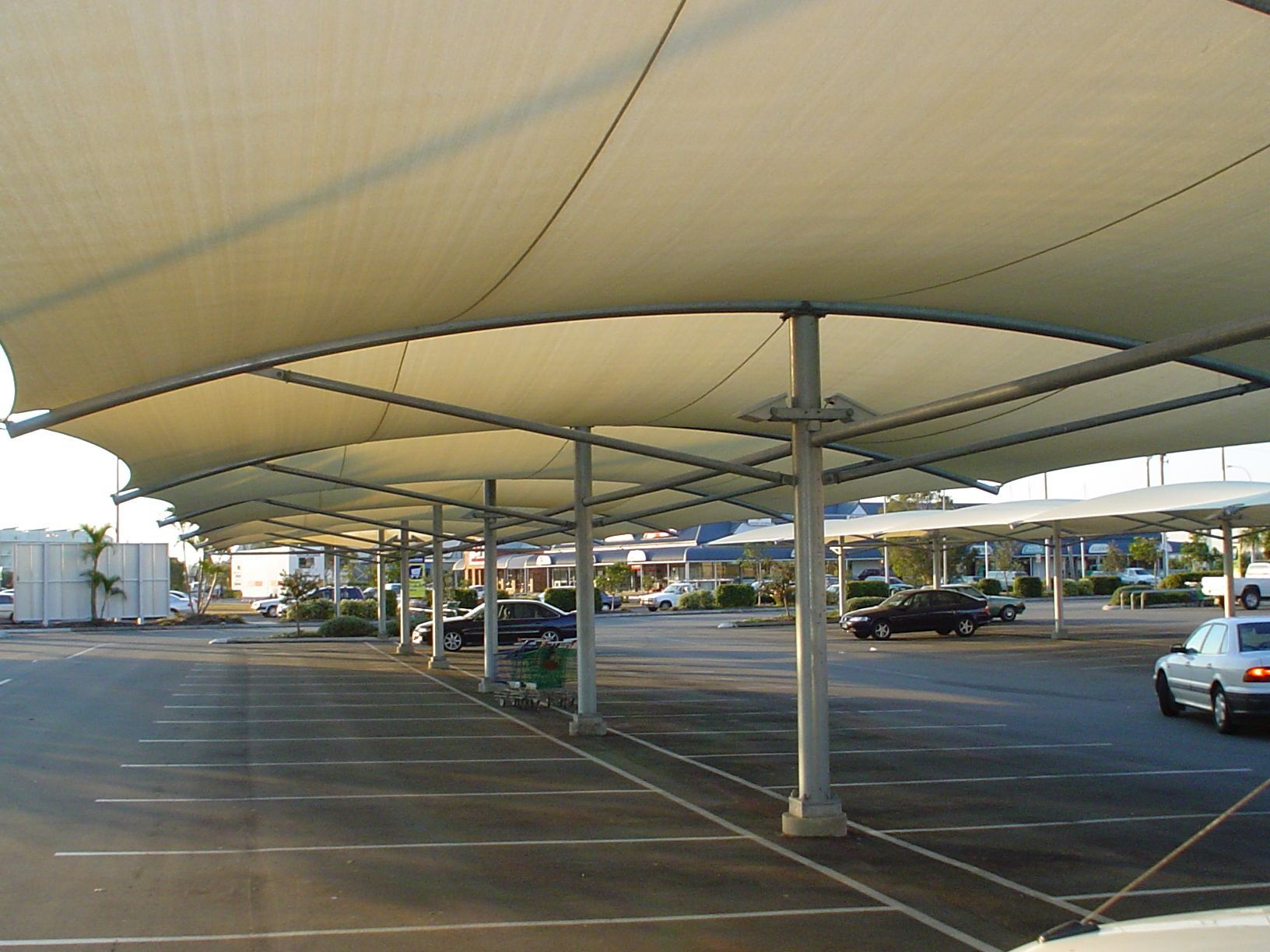 A Large, Beige Shade Canopy Covers a Parking Lot Area — The Gazebo and Shade Centre in Jindera, NSW
