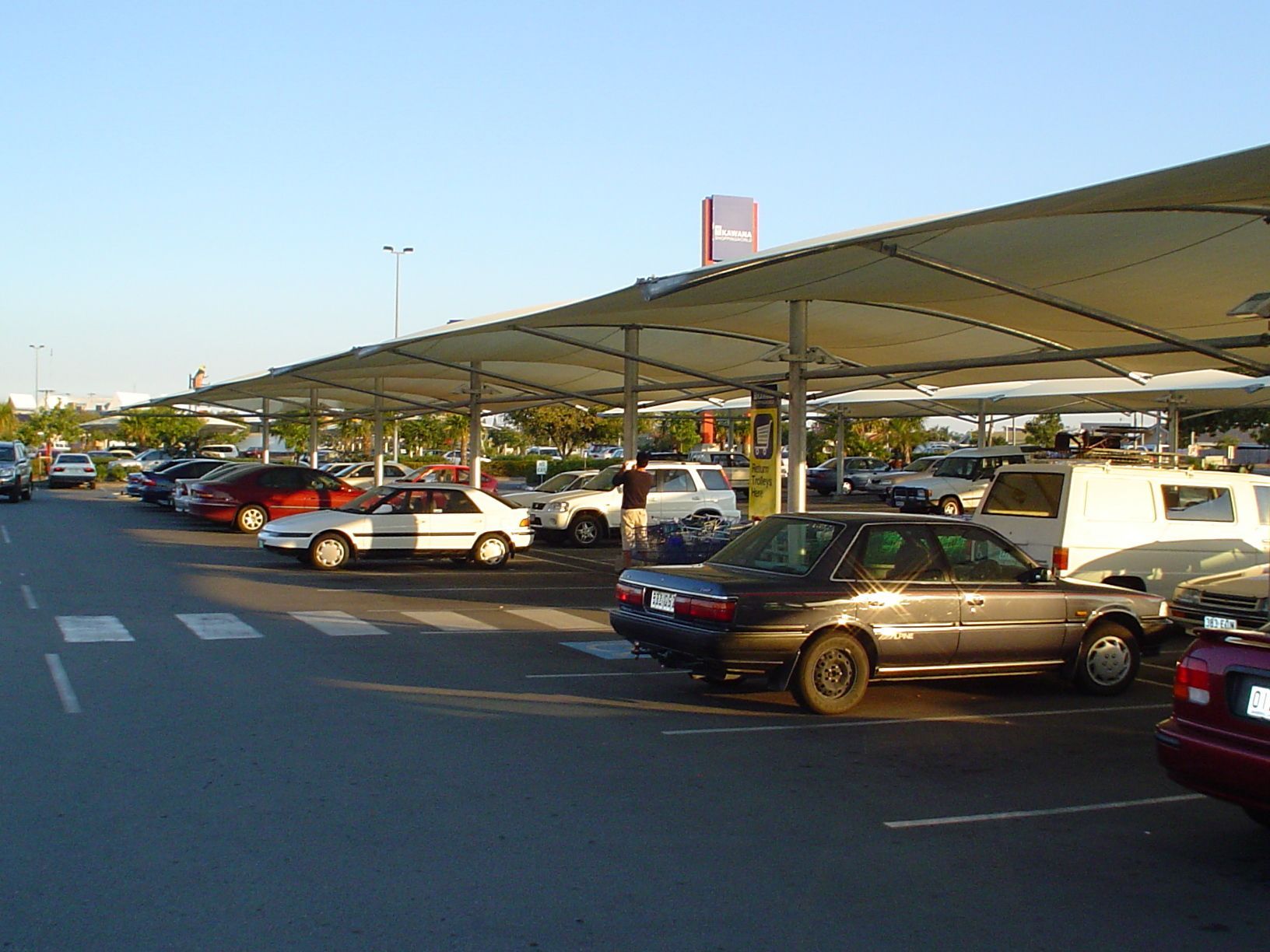 A Parking Lot With Several Cars Parked Under a Large Fabric Shade — The Gazebo and Shade Centre in Jindera, NSW