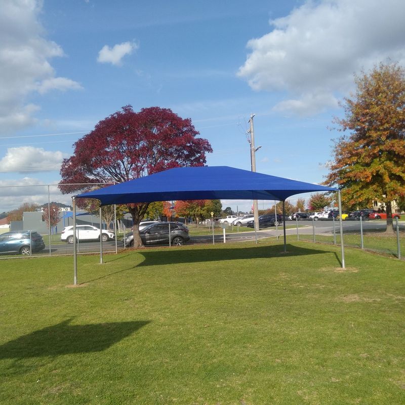 A Blue Rectangular Shade Sail Structure Stands on a Grassy Field — The Gazebo and Shade Centre in Jindera, NSW