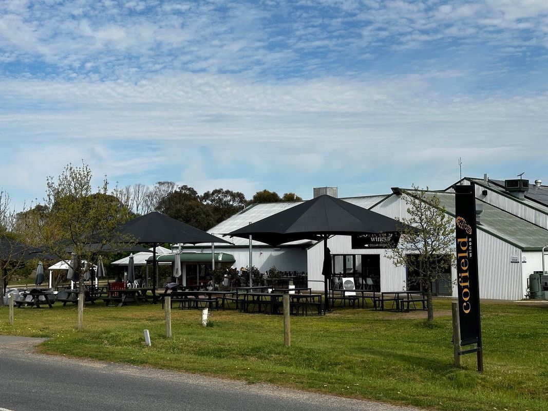 A White Building With Dark Umbrellas Over an Outdoor Patio Area — The Gazebo and Shade Centre in Jindera, NSW