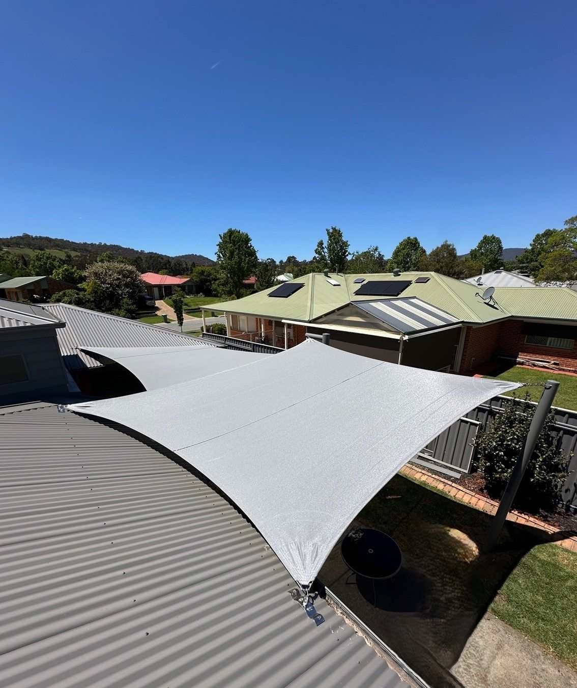 Shaded outdoor area with white canopy sails over buildings under a clear blue sky — The Gazebo and Shade Centre in Wangaratta, VIC