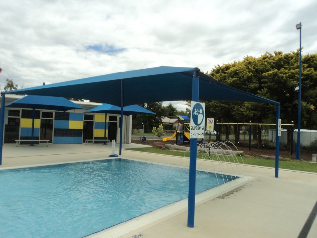 A Swimming Pool Outdoors Shaded by a Large Blue Canopy Structure — The Gazebo and Shade Centre in Jindera, NSW