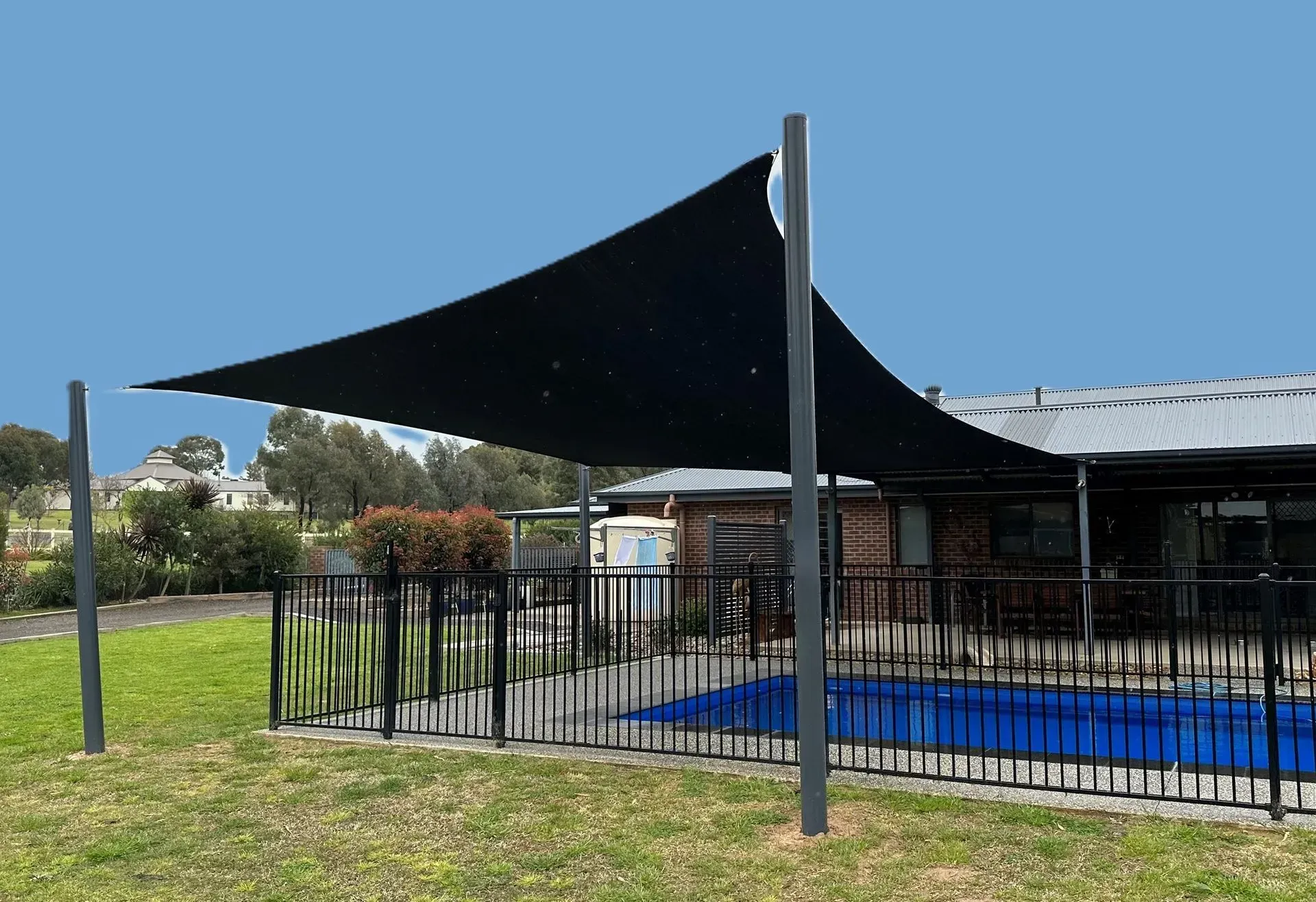 A Large, Black Triangular Shade Sail Suspended Over a Backyard — The Gazebo and Shade Centre in Jindera, NSW