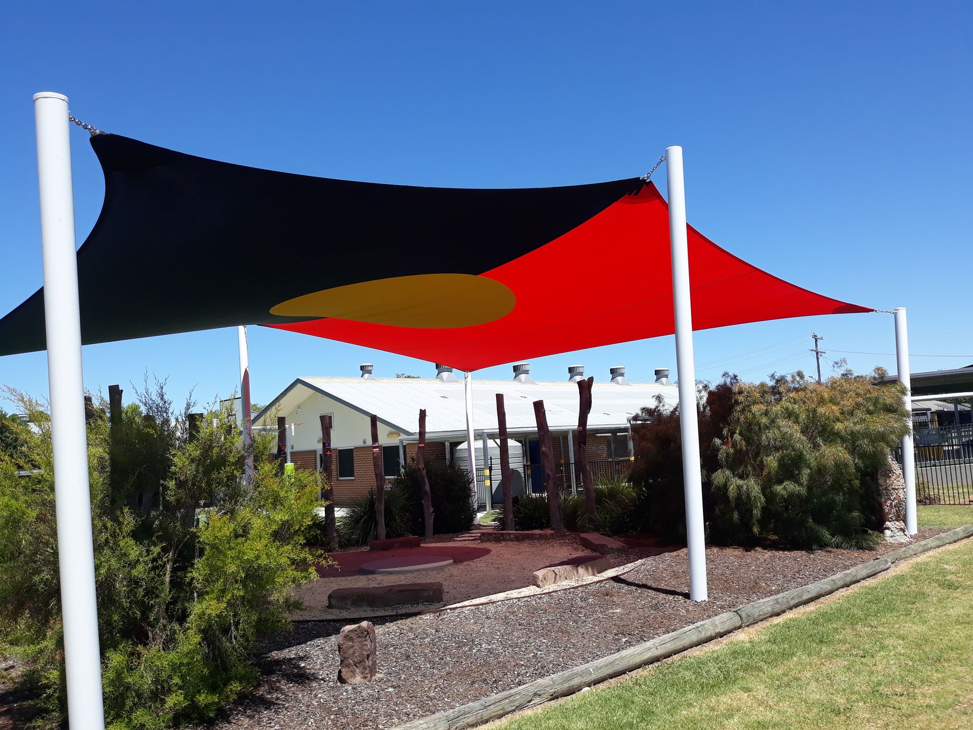 Outdoor shade sails in black and red over a patio in a landscaped yard  — The Gazebo and Shade Centre in Jindera, NSW