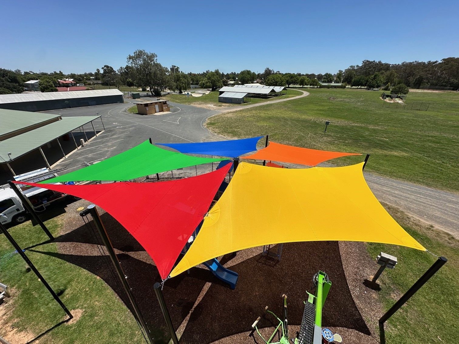 Colourful shade sails over a grassy outdoor area on a sunny day — The Gazebo and Shade Centre in Wangaratta, VIC