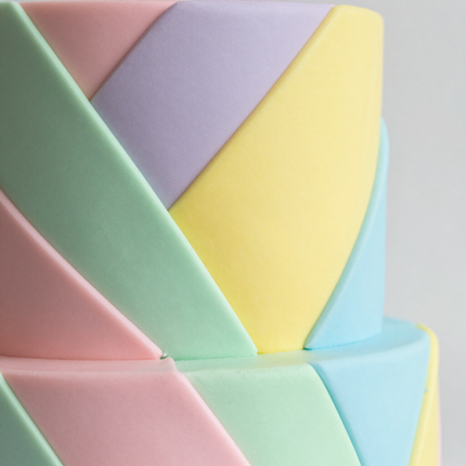 Pastel geometric cake with folded fondant panels in pink, mint, yellow, lavender, and blue